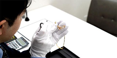 商品を査定するVサインのスタッフ